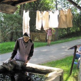 A woman at the village lavoir, or clothes washing place. Sinks are fed from a natural water source and sheltered by a roof. One of the centres of village life.